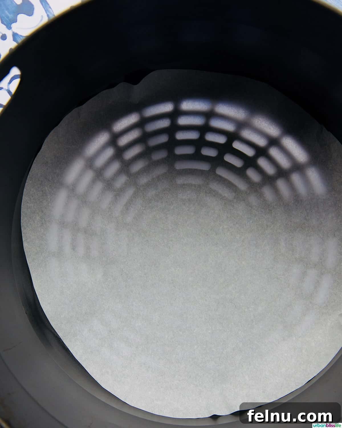 Parchment paper carefully placed into an air fryer basket, ready for cooking.