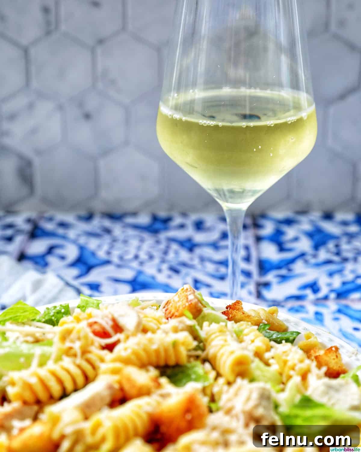 Creamy Caesar Pasta Salad with Crispy Croutons 11 glass of white wine and bowl of Caesar pasta salad.