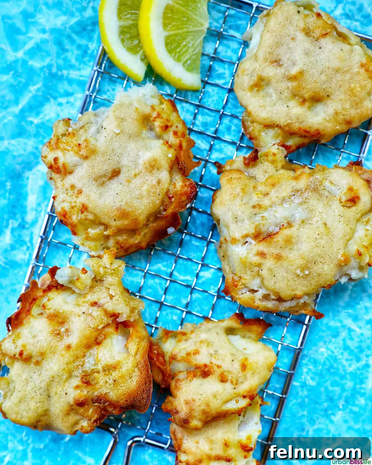 Crispy Air Fryer Cod with Lemon Garlic Butter 5 air fryer cod pieces on a fish grid with lemon wedges.